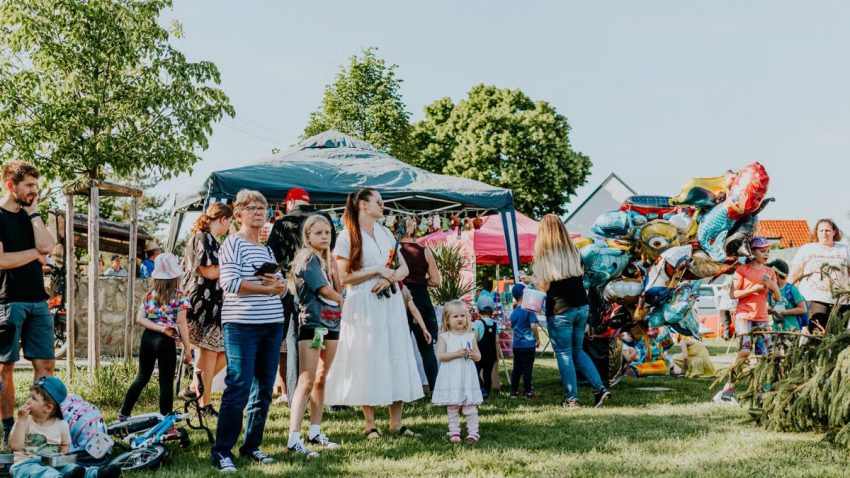 A lively outdoor gathering with families enjoying balloons and a sunny day.